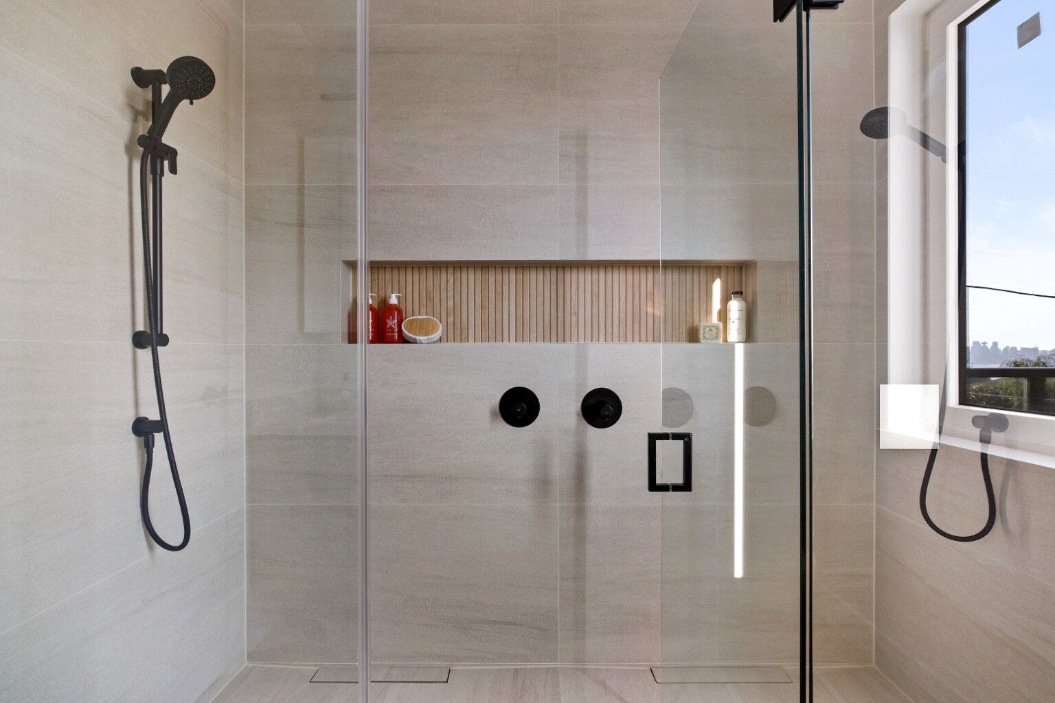 Primary bathroom shower with integrated niche and black fixtures