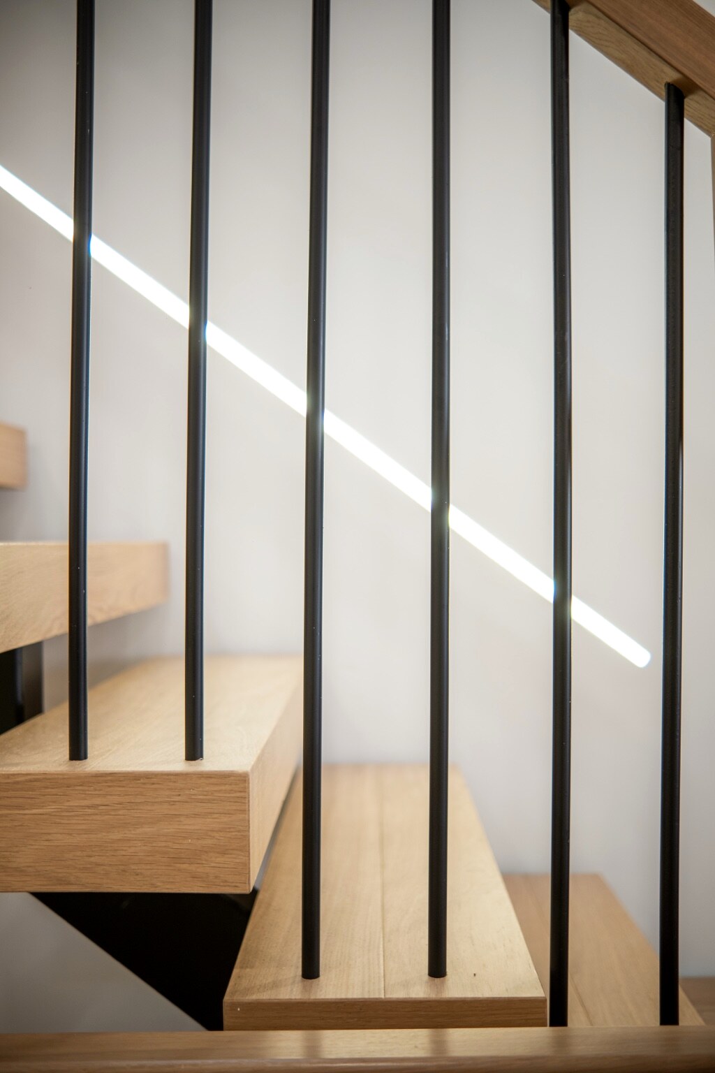 Oak stair treads, steel balusters, and integrated linear lighting
